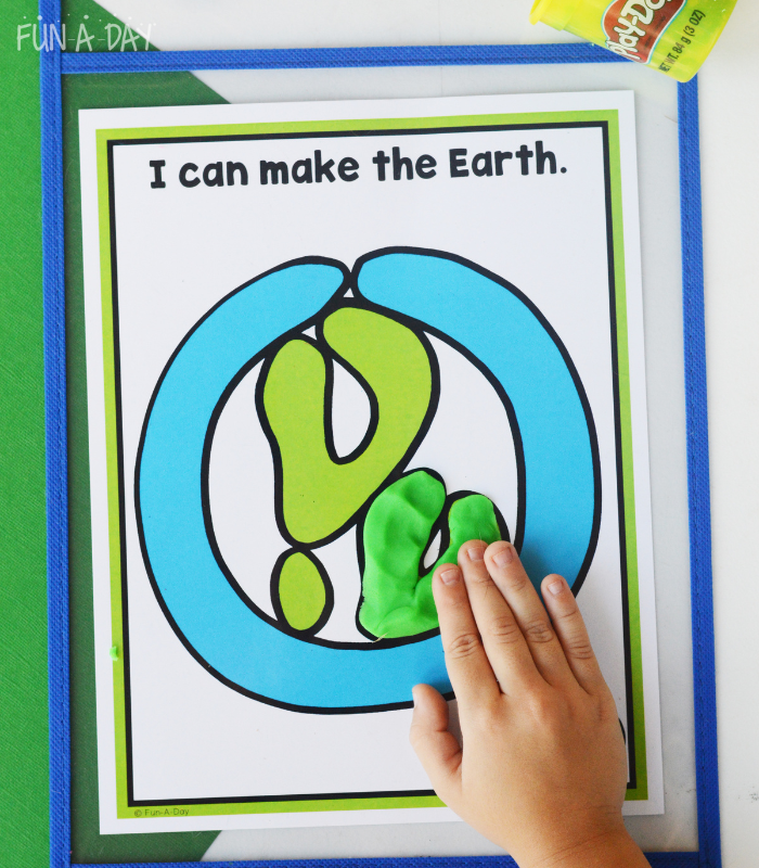 preschooler adding green dough to Earth play dough mat