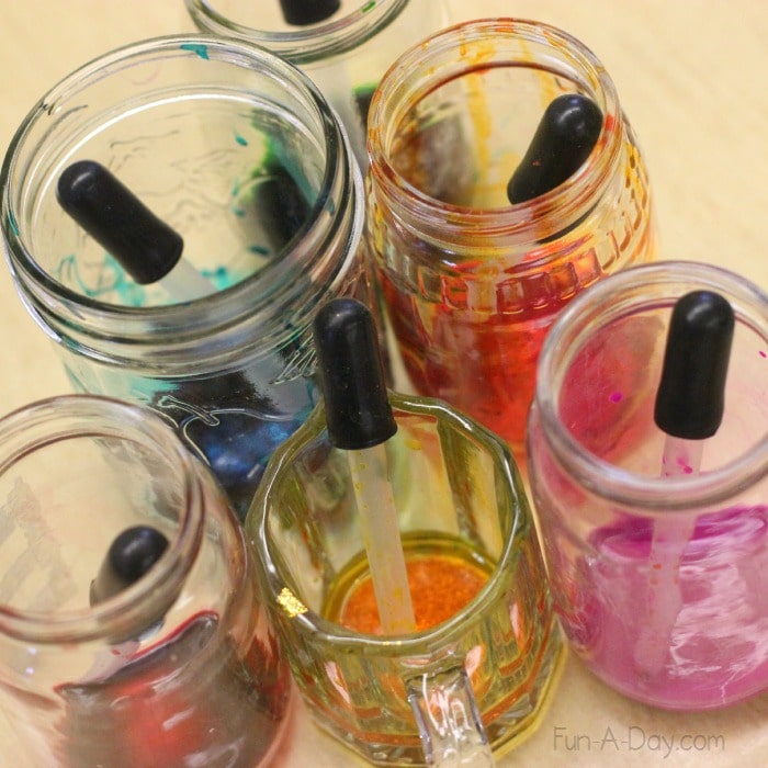 small glass jars containing liquid watercolors and eye droppers to make coffee filter flowers