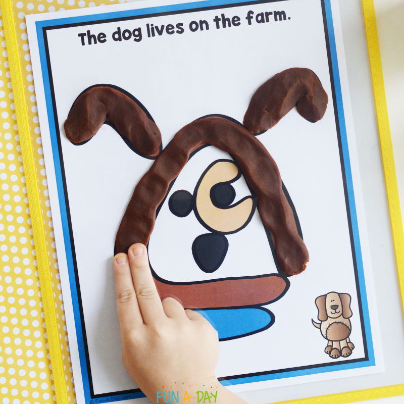preschooler adding brown play dough to a dog playdough mat
