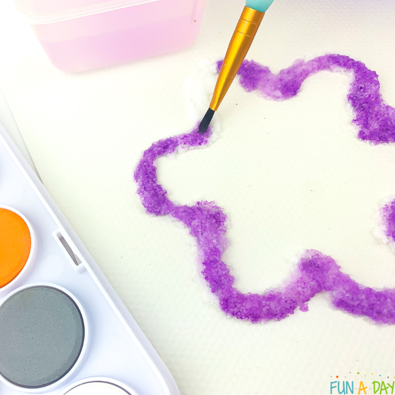 paintbrush adding purple watercolors to flower raised salt painting