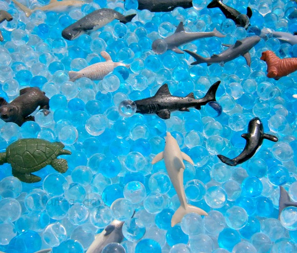 ocean animal toys in bin of blue and clear water beads