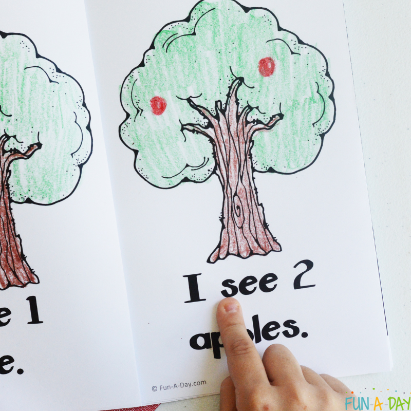 preschooler pointing to words in printable apple counting book