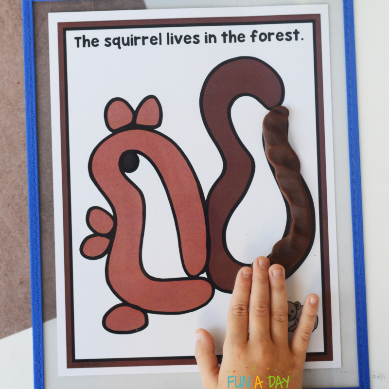 child using dough to make a squirrel on one of the forest animal playdough mats
