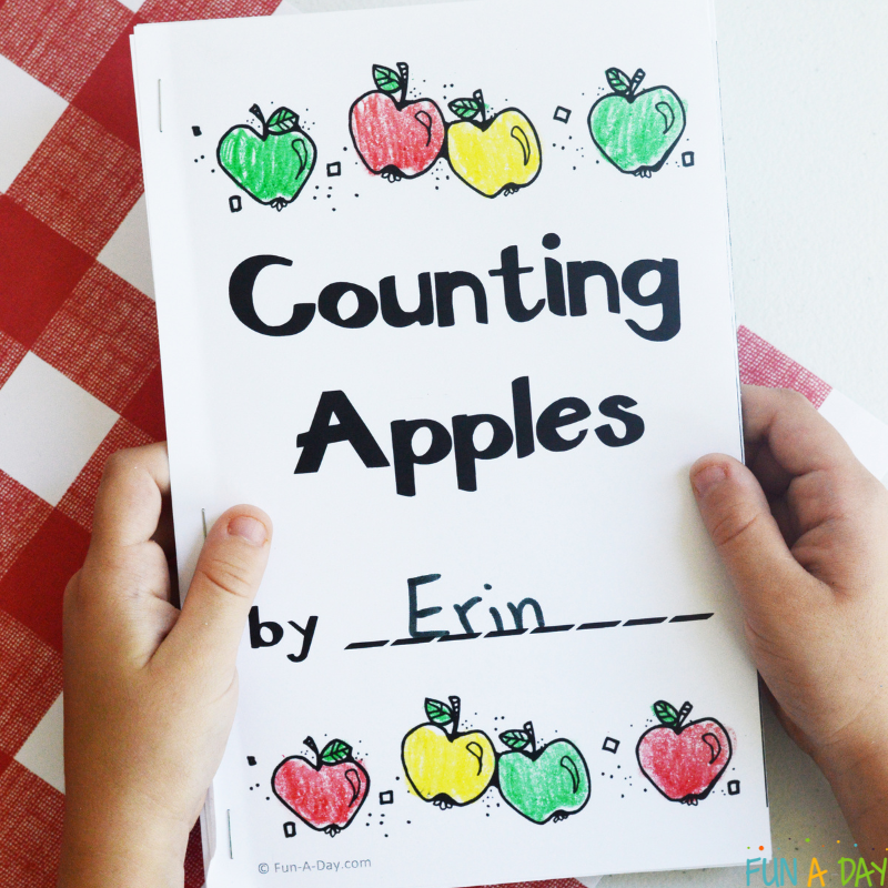 preschool student holding assembled printable apple counting book