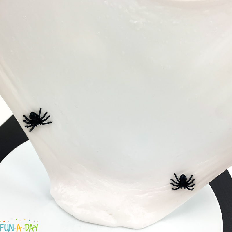 white slime being stretched thin, with 2 black spider toys in it
