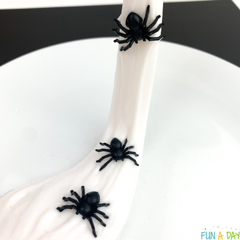 white slime with 3 black toy spiders in it