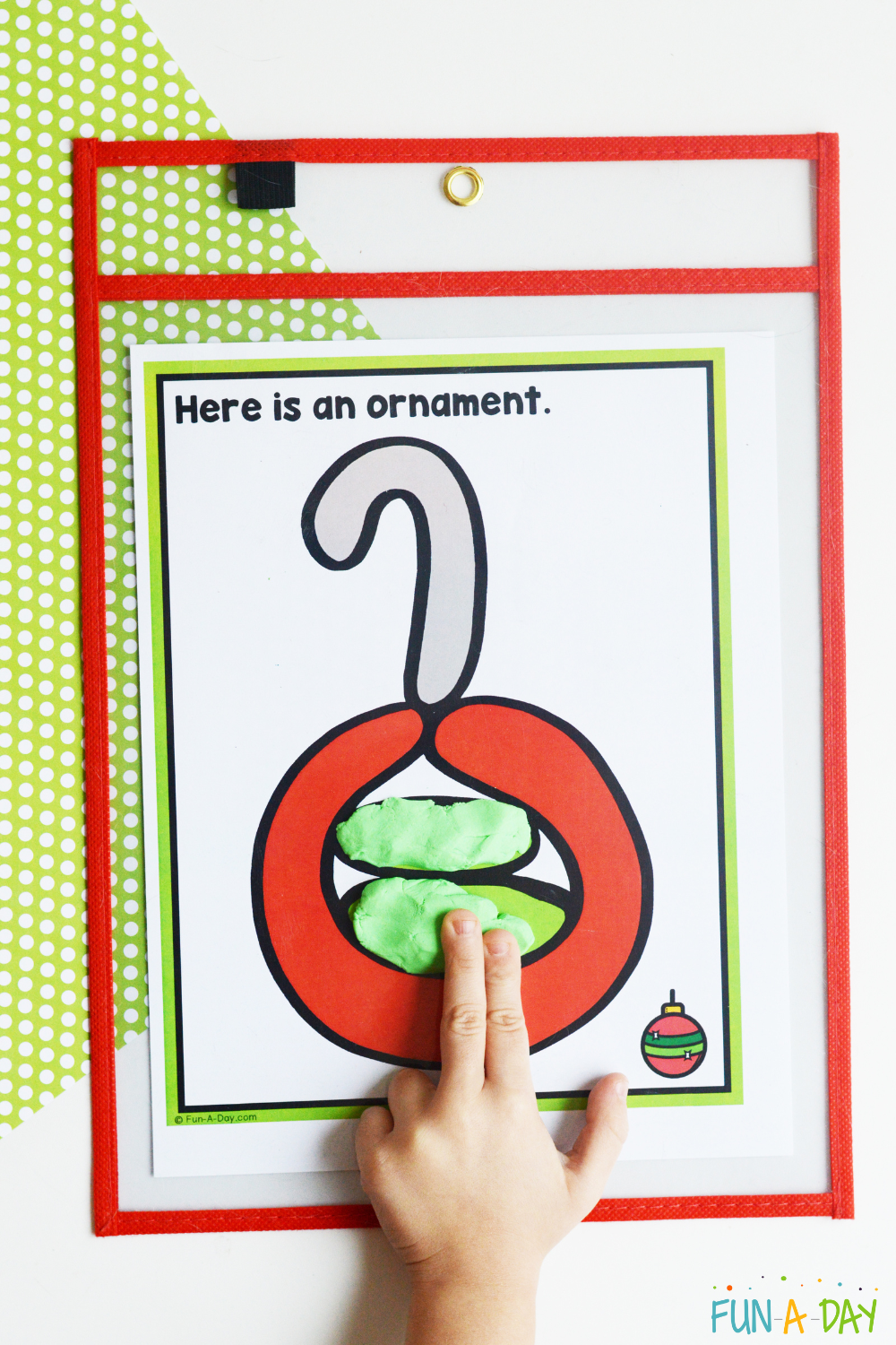child placing green dough on one of the christmas playdough mats with an ornament on it