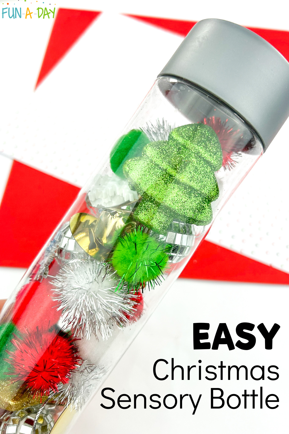 clear bottle filled with pom poms, bells, glittery trees, etc. with text that reads easy Christmas sensory bottle
