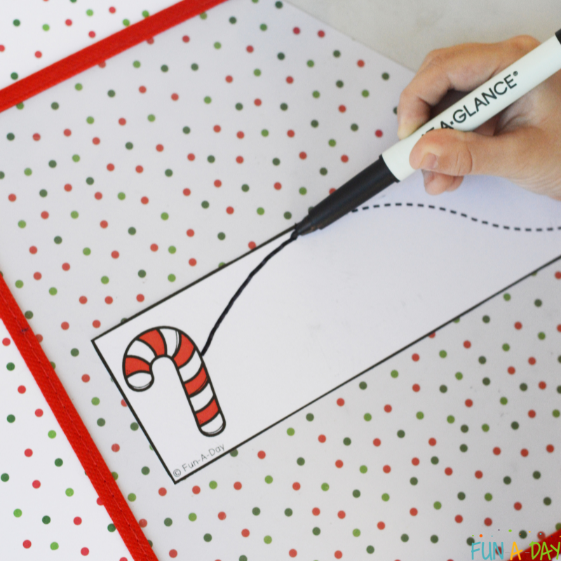 child using dry erase marker to trace over dotted line on one of the christmas cutting strips