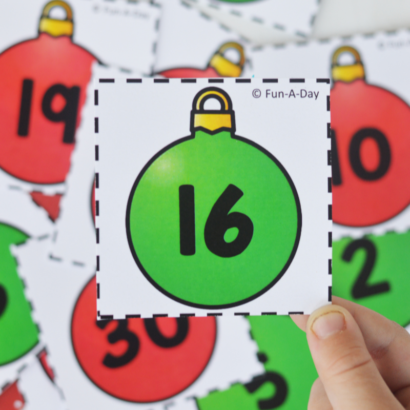 child holding number 16 card above a pile of ornament calendar numbers