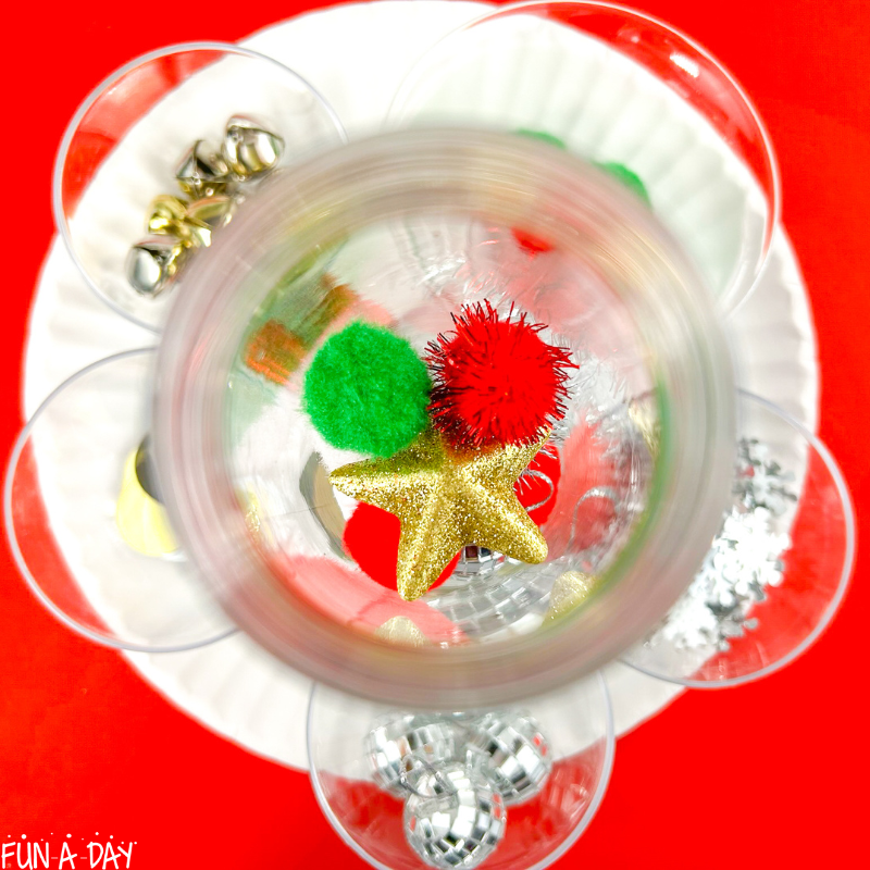 view inside a christmas sensory bottle as it's being assembled - pom poms and star are visible inside bottle