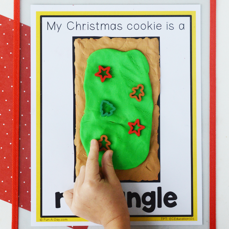 preschooler adding manipulatives atop play dough spread over rectangle christmas cookie shape mat