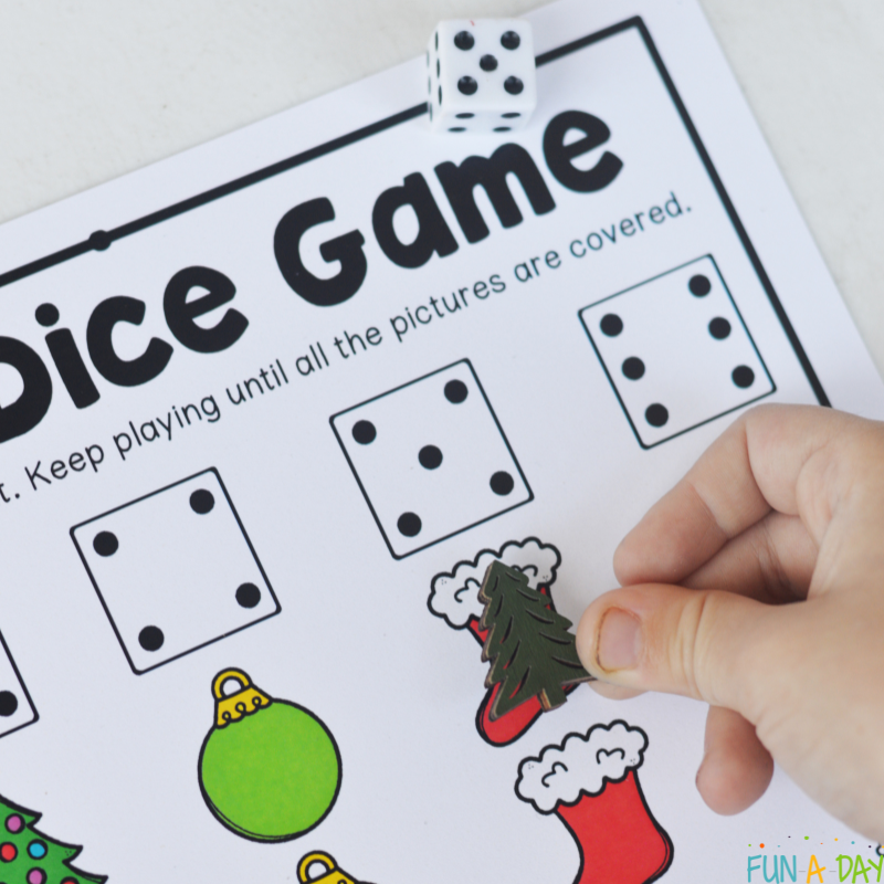 child adding tree manipulative to printable christmas dice game