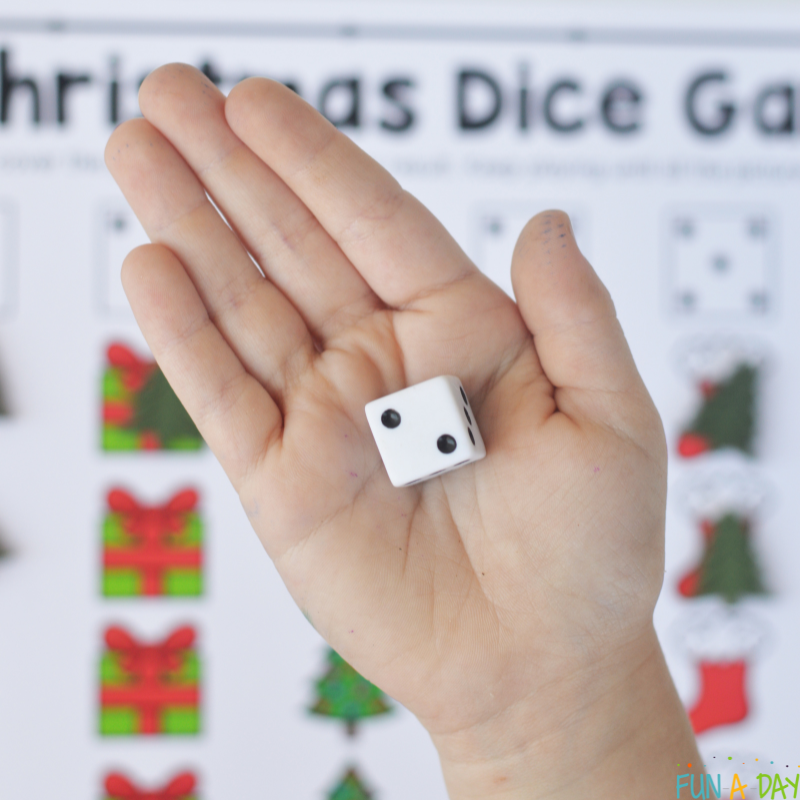 preschooler holding a die in their hand over christmas dice game printable