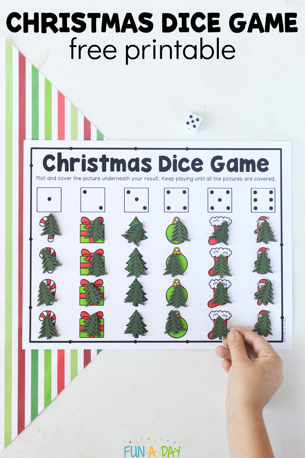 child placing manipulatives on printable Christmas game with text that reads Christmas dice game free printable