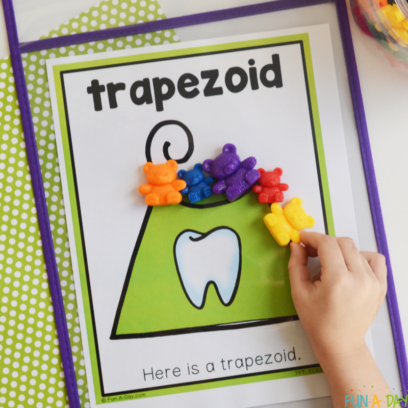 preschooler using counting bears to trace trapezoid-shaped floss on dental shape mat