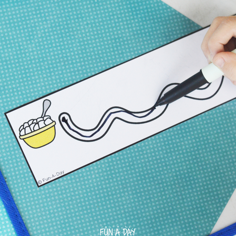 child using dry erase marker to trace a line on hot chocolate tracing strips