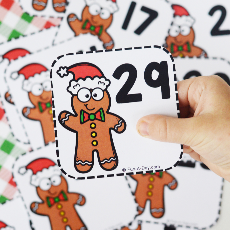 preschooler holding number 29 card over pile of gingerbread man calendar numbers