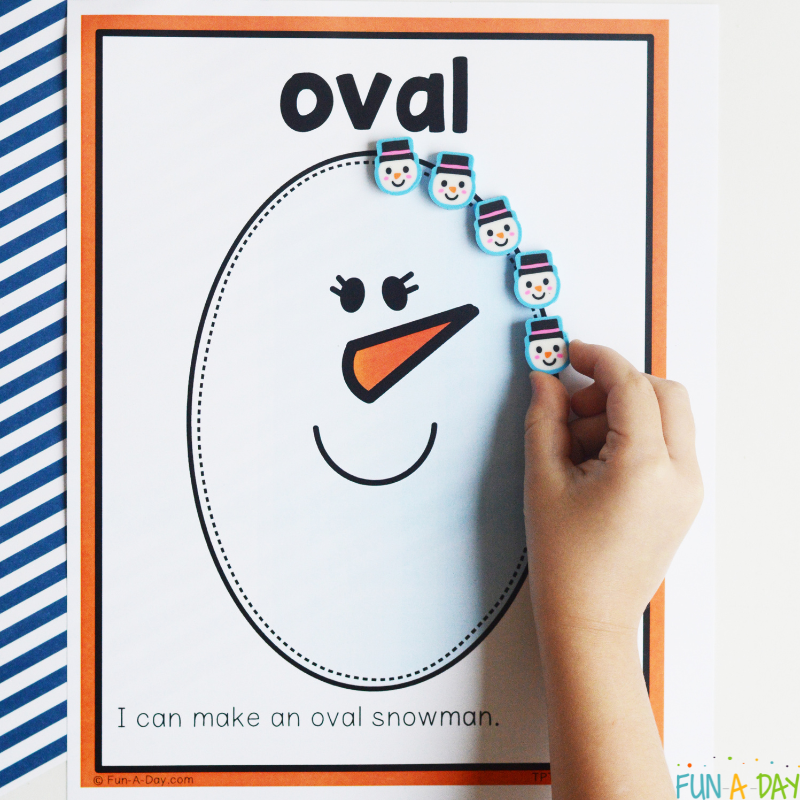 preschooler tracing oval snowman with mini erasers on one of the snowman shape mats