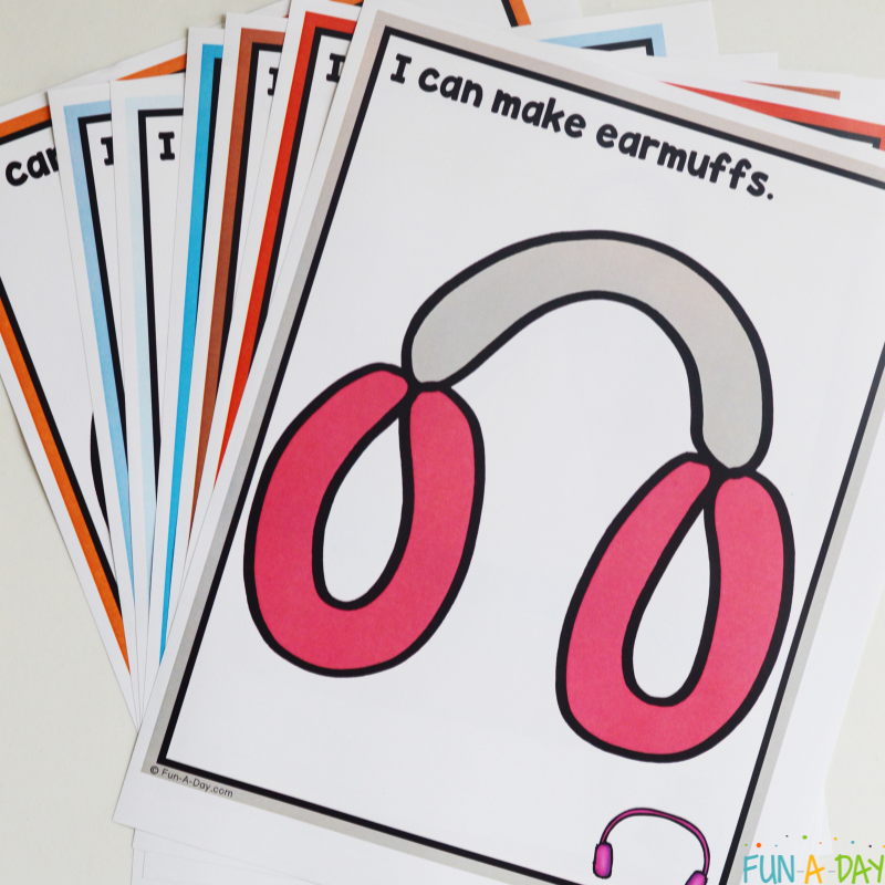 Stack of winter playdough mats topped with the earmuff mat with text that reads I can make earmuffs.