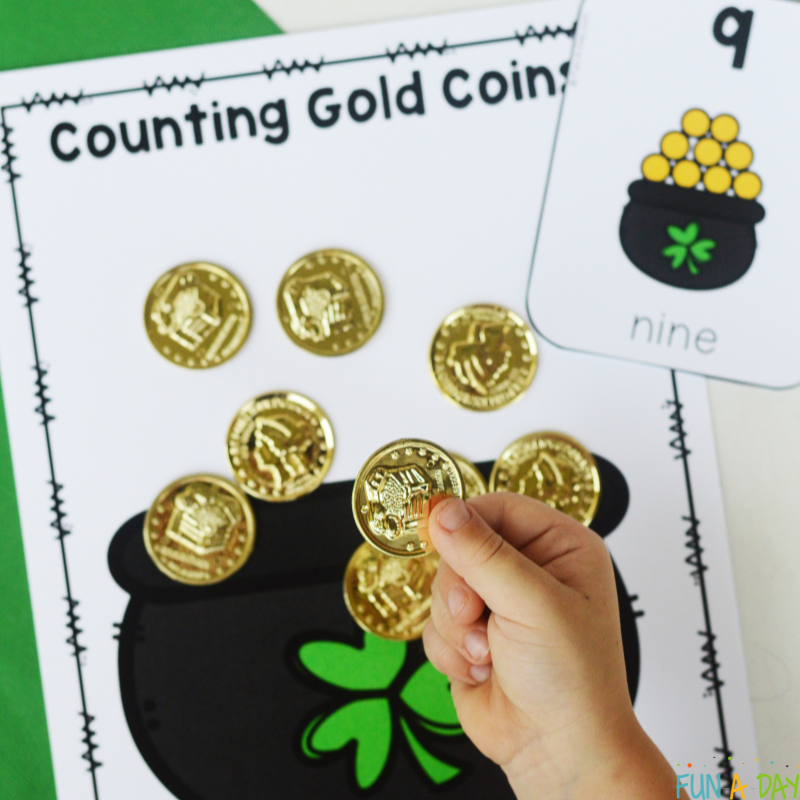 child adding 9 plastic gold coins to st. patrick's day printable counting mat