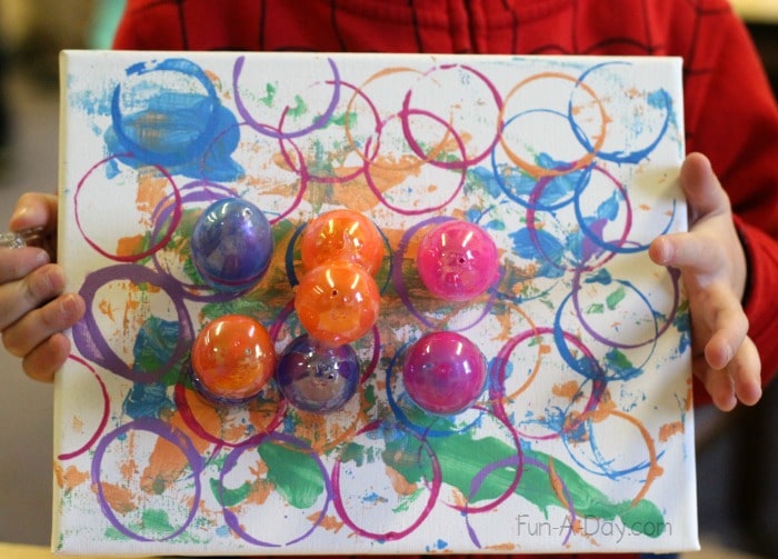 preschooler holding finished egg art project on canvas