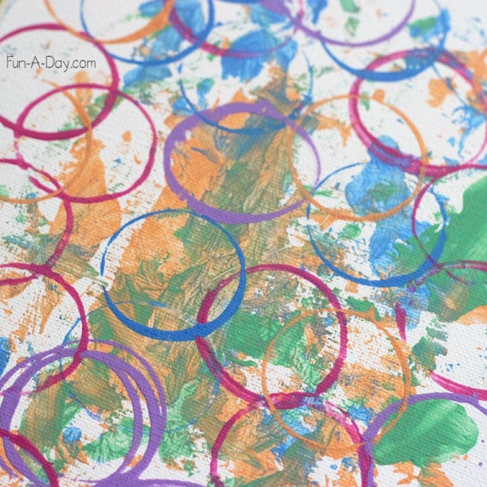 close up of canvas with plastic egg prints and egg rolling paint as part of a preschool egg art project