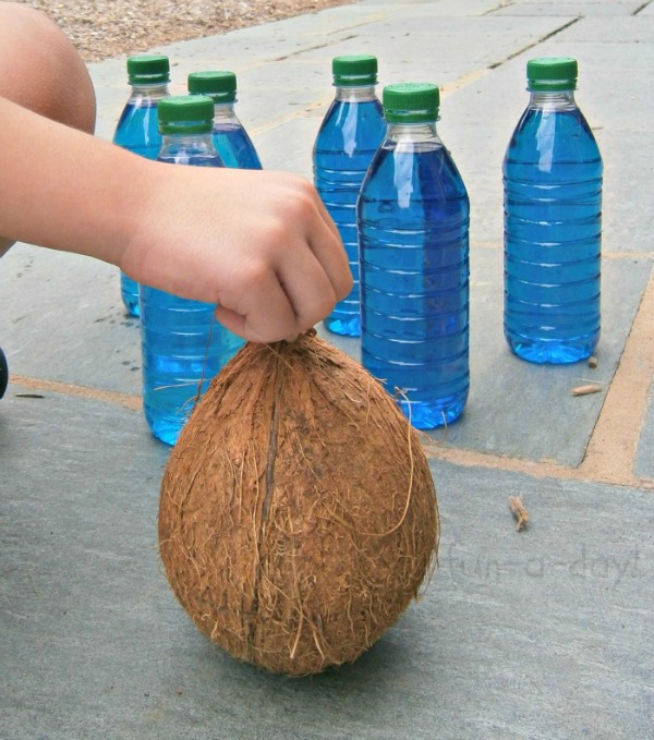 preschooler placing coconut in front of homemade bowling pins for game