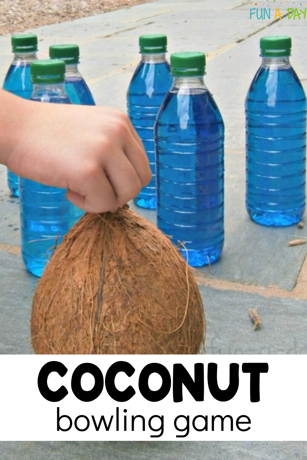child's hand holding coconut in front of filled bottles with text that reads coconut bowling game