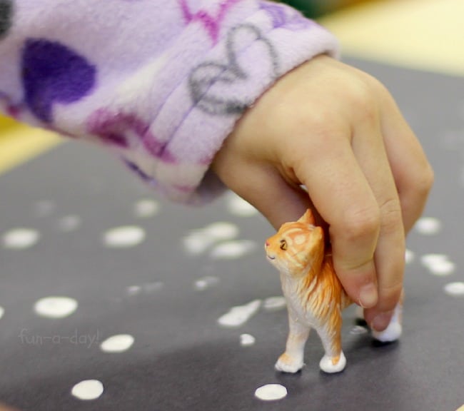 preschooler using cat toy to stamp paint onto paper