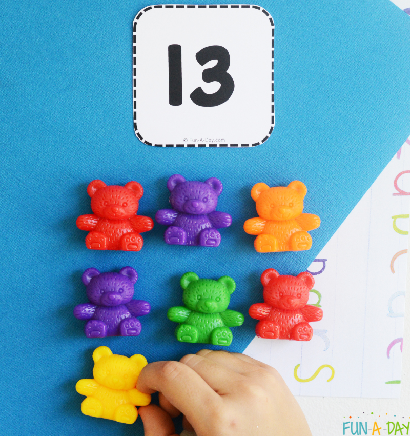 child adding counting bear manipulatives underneath printable number card 13
